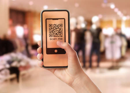 Woman holding smartphone with QR code on screen in store, closeupの写真素材