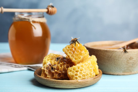 Fresh delicious honeycombs and bees on light blue wooden table