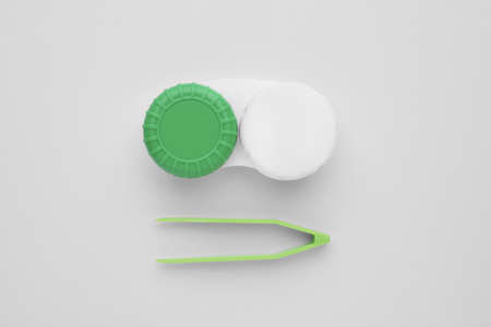 Case with contact lenses and tweezers on white background, flat lay