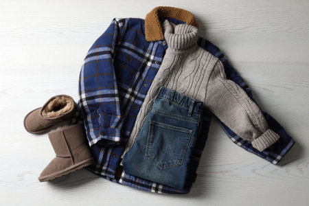 Warm child clothes and shoes on white wooden background, flat layの写真素材