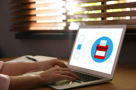 Woman voting online via laptop at table, closeupの写真素材