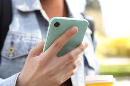Woman using smartphone outdoors on sunny day, closeupの写真素材
