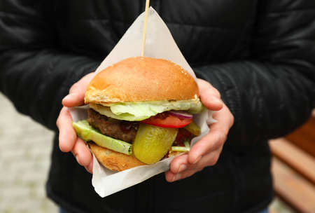 Woman holding fresh delicious burger outdoors, closeup. street foodの写真素材