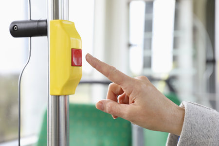Woman pressing stop button in public transport, closeup