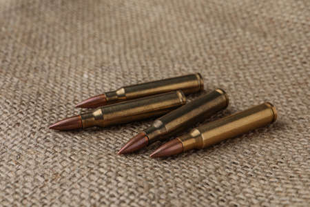 Many brass bullets on burlap, closeup. Fire arm ammunition