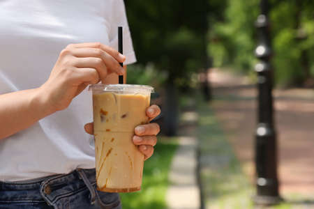 Woman holding takeaway plastic cup with cold coffee drink outdoors, closeup. Space for textの写真素材