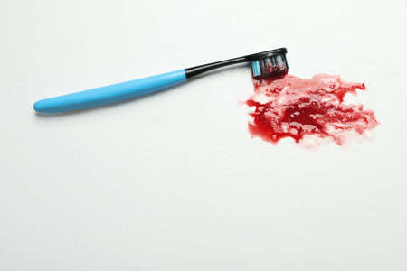Toothbrush with blood on white table, top view and space for text. gum inflammation