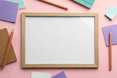 Blank white board with stationery on light pink background, flat lay. Space for textの写真素材