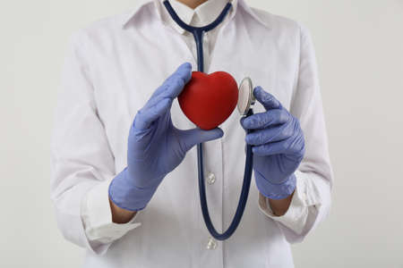 Doctor with stethoscope and red heart on white background, closeup. cardiology conceptの写真素材