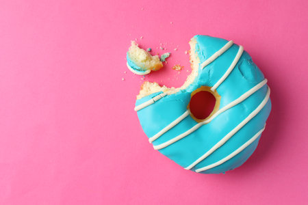 Sweet bitten glazed donut on pink background, top view. Space for textの写真素材