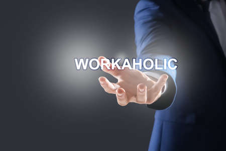 Businessman and word Workaholic on dark gray background, closeup