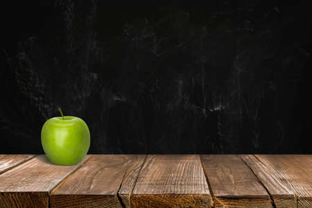 Fresh ripe green apple on wooden table near black chalkboard, space for textの写真素材