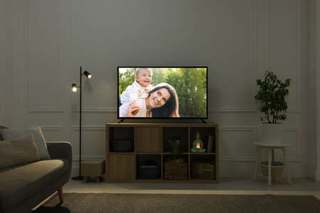 Modern TV set on wooden stand in room