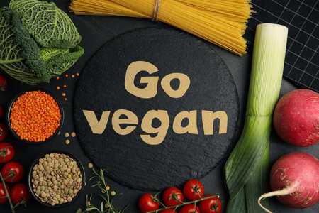 Slate plate with phrase Go Vegan and fresh products on black background, flat layの写真素材
