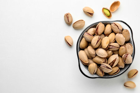 Bowl and pistachio nuts on white background, flat lay. Space for textの写真素材
