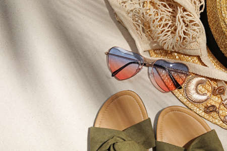 Flat lay composition with stylish sunglasses and other fashionable accessories on sand. Space for...