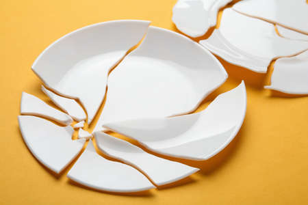 Two broken ceramic plates on orange background, closeupの写真素材