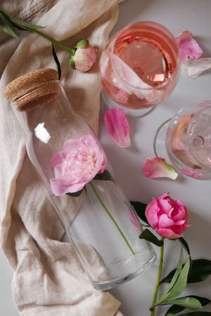 Flat lay composition with rose wine and beautiful pink peonies on white backgroundの写真素材