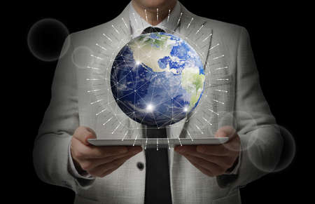 Internet technology concept. Man holding tablet and virtual icon of Earth on dark background