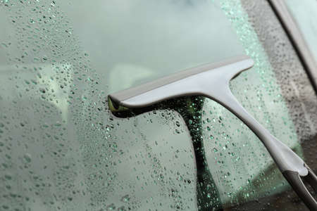 Wiping car window with drying blade outdoors, closeup