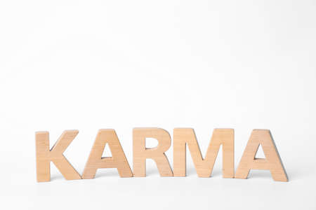Word Karma made of wooden letters on white background, space for text