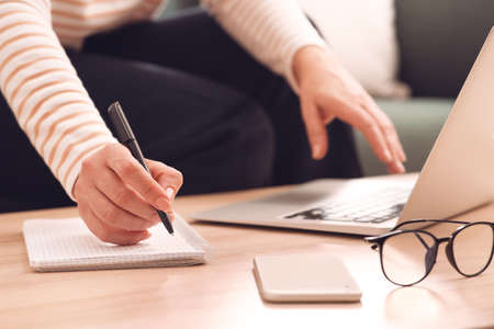 Woman with modern laptop learning at table indoors, closeup