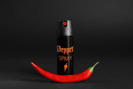Bottle of gas spray and fresh chili pepper on black backgroundの写真素材
