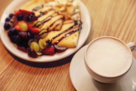 Cup of aromatic coffee and delicious desserts on wooden table, closeupの写真素材
