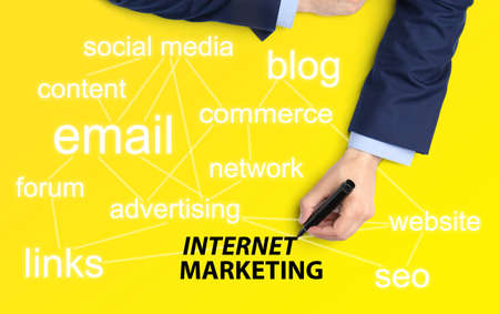 internet marketing. Different words and businessman with marker on yellow background, top viewの写真素材