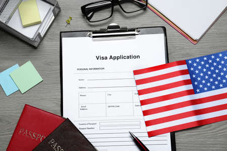 Visa application form, American flag, passports and stationery on wooden table, flat layの写真素材