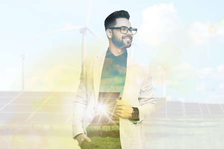 Multiple exposure of businessman, wind turbines and solar panels installed outdoors. alternative energy sourcesの写真素材