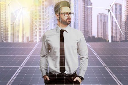 Multiple exposure of businessman, wind turbines and solar panels installed outdoors. alternative...