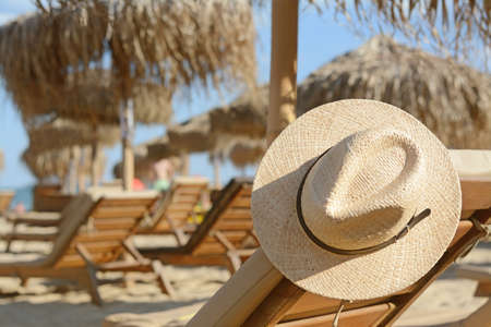 Stylish straw hat on wooden sunbed at beach, space for textの写真素材