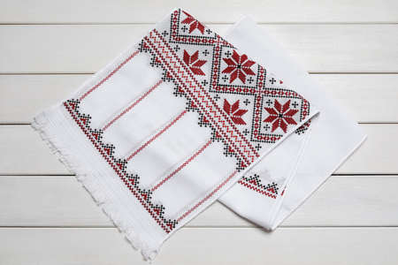 Beautiful rushnyk on white wooden table, top view. Ukrainian national embroideryの写真素材