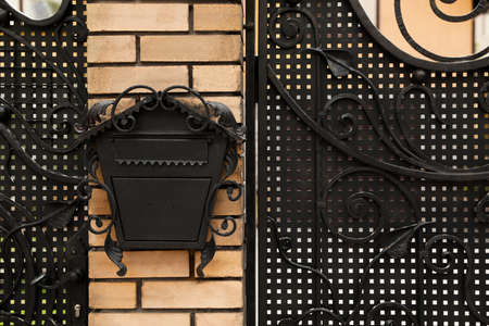 Vintage letter box on beige brick wall near fence outdoorsの写真素材
