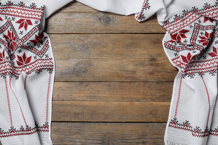 Beautiful rushnyk on wooden table, top view with space for text. Ukrainian national embroidery