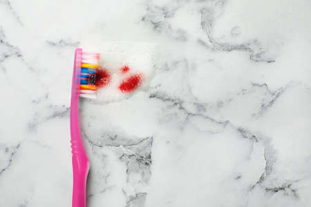Brush, toothpaste foam with blood on white marble table, top view and space for text. gum problemsの写真素材