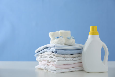 Detergent and children's clothes on white table near blue wallの写真素材