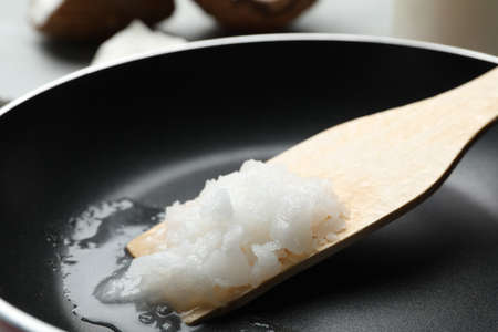 Frying pan with coconut oil and wooden spatula, closeup. Healthy cookingの写真素材