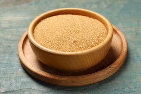 Brown sugar in bowl on light blue wooden tableの写真素材
