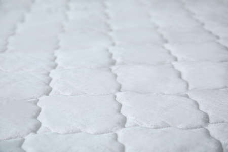 New white mattress as background, closeup view