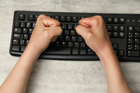 Angry man with clenched fists at table during work, top viewの写真素材
