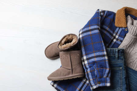 Warm child clothes and shoes on white wooden background, flat lay. Space for textの写真素材