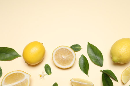 Many fresh ripe lemons with leaves and flower on beige background, flat lay. Space for textの写真素材