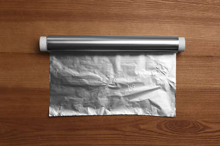 Roll of aluminum foil on wooden table, top viewの写真素材