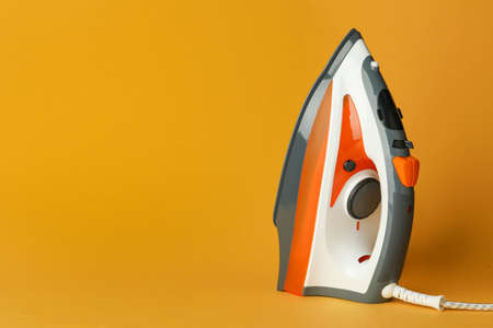One modern iron on orange background, space for text. home appliancesの写真素材