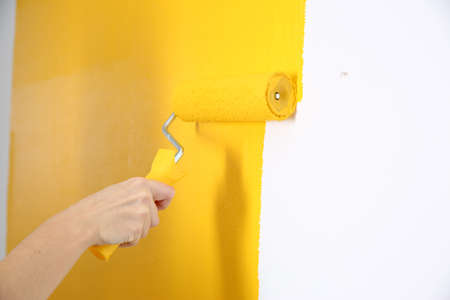 Woman painting white wall with yellow dye, closeup. interior renovationの写真素材