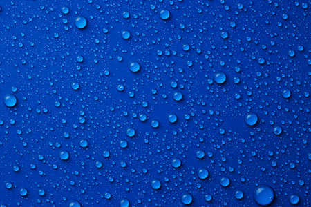 Water drops on blue background, top view