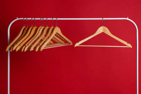 Wooden clothes hangers on metal rack against red backgroundの写真素材