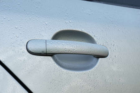 Close up view of car door handle with water drops